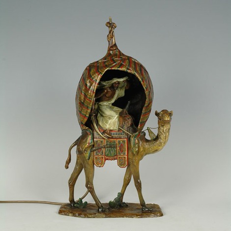 cold painted bronze lamp of a camel with an Arab warrior seated inside a tentedawning on a naturalistic base